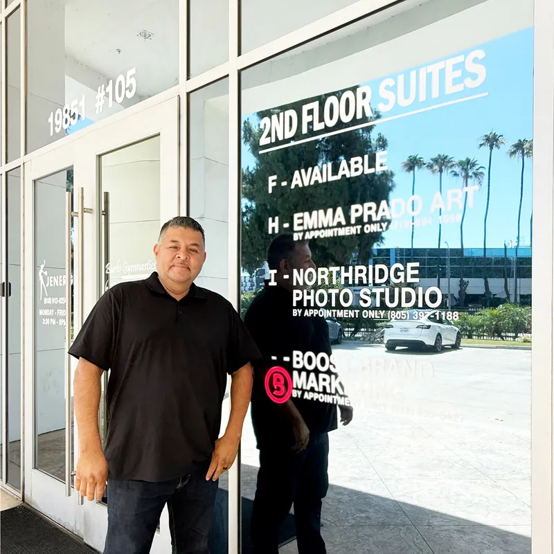 Man standing outside the studio entrance next to the building directory sign