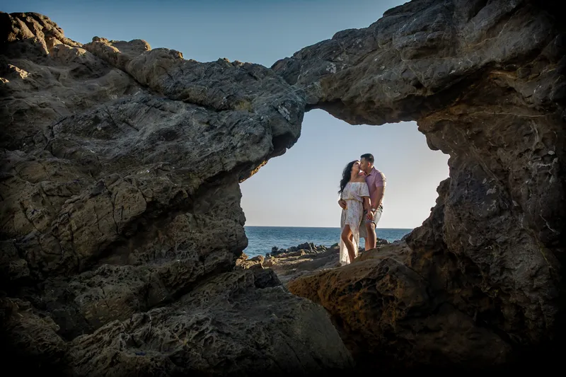 Engaged couple kissing inside a natural rock arch overlooking the ocean, Northridge Photo Studio engagement session