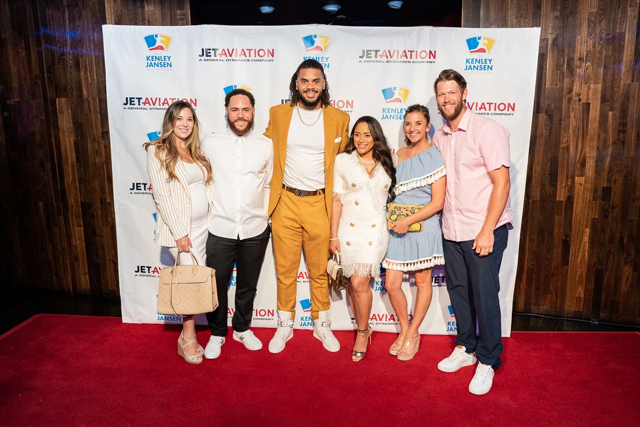 Group of guests posing together at a step and repeat banner at an evening charity event