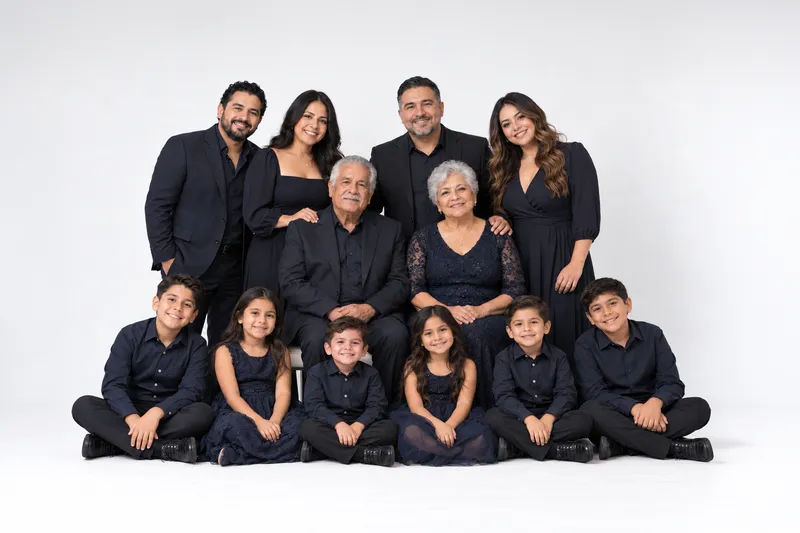 Large extended family in coordinated black outfits posing together on a white studio backdrop, different arrangement