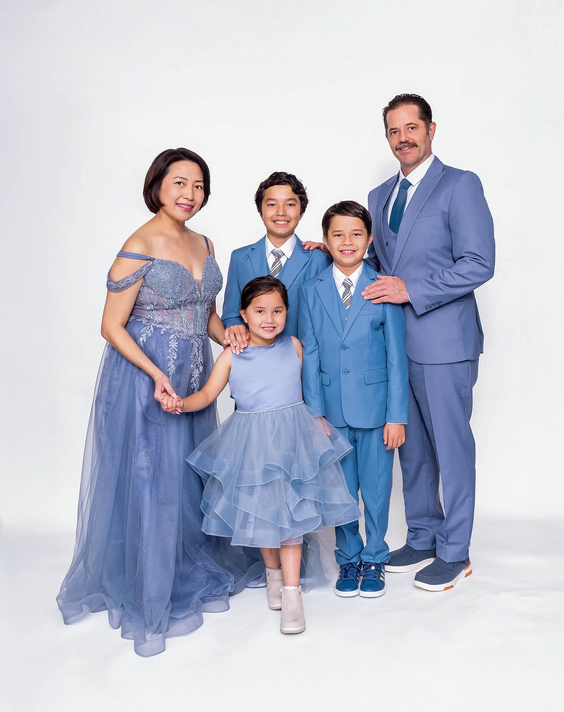 Family of five in coordinated blue outfits for a studio family portrait