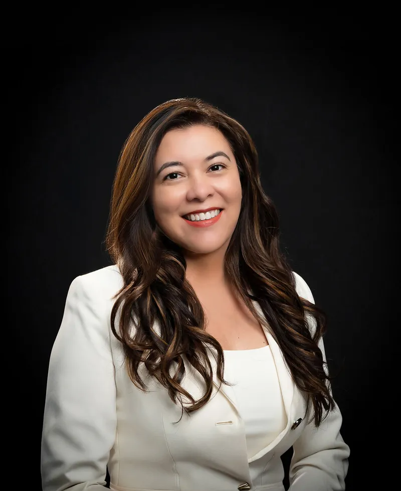 Personal branding portrait of a woman in a white blazer against a black backdrop
