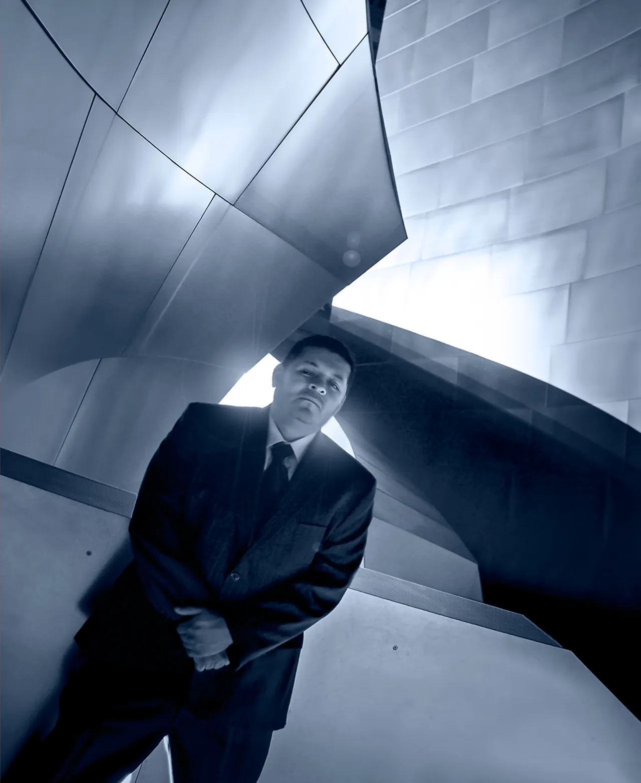 Editorial portrait of a man in a suit photographed with dramatic architectural lines in blue tone