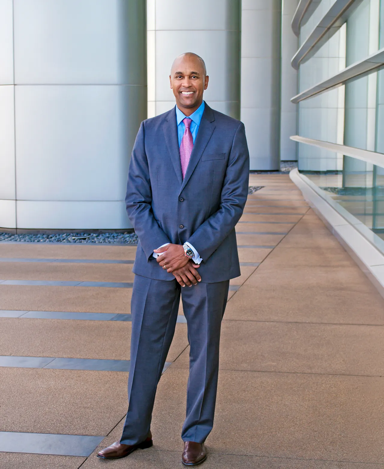 Personal branding portrait of a man in a suit standing in a modern architectural walkway