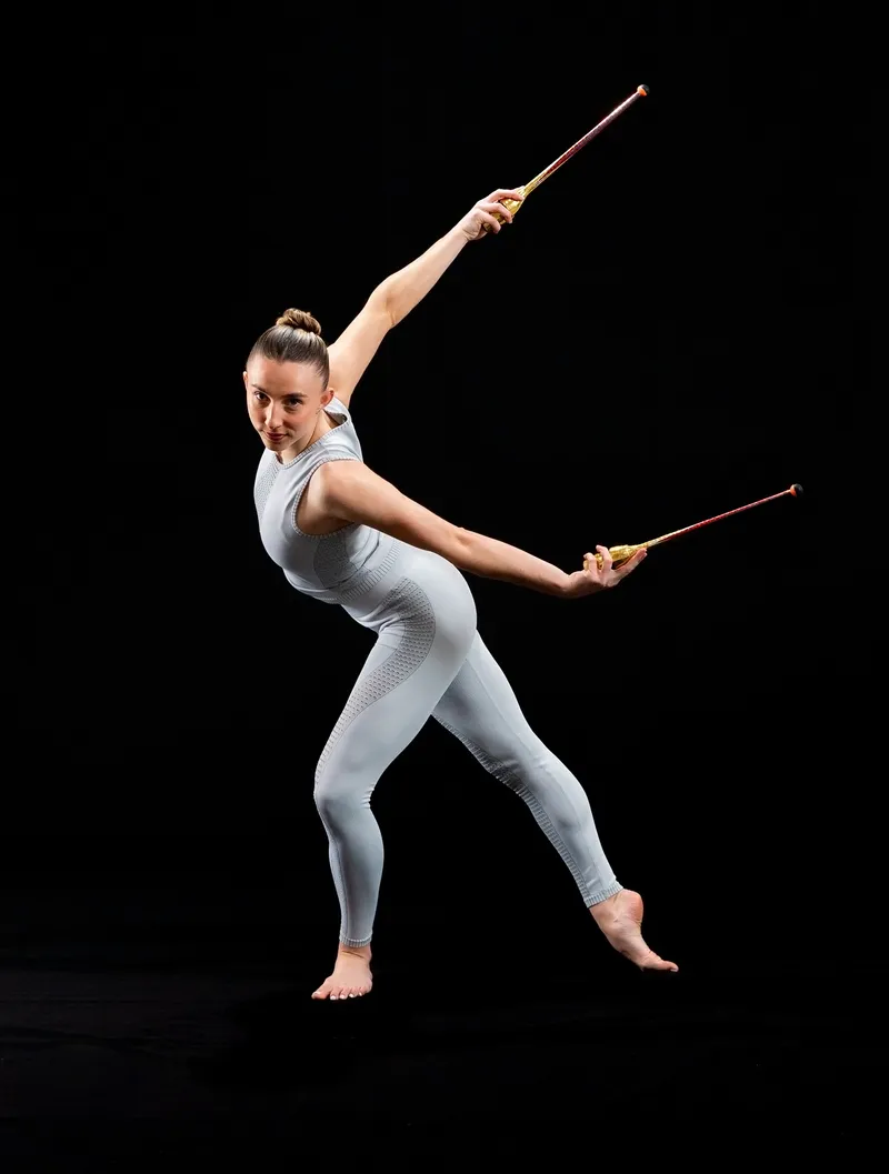 Gymnast captured mid-routine holding rhythmic gymnastics clubs