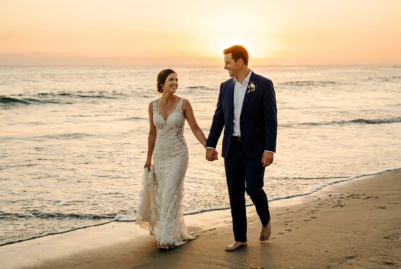 Bride and groom walking together on the beach at sunset